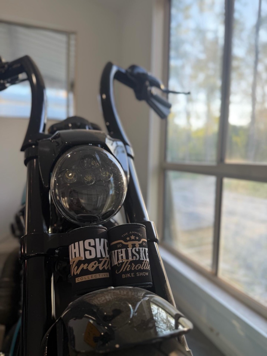 Custom Whiskey Throttle Collective event stubby coolers displayed on a motorcycle